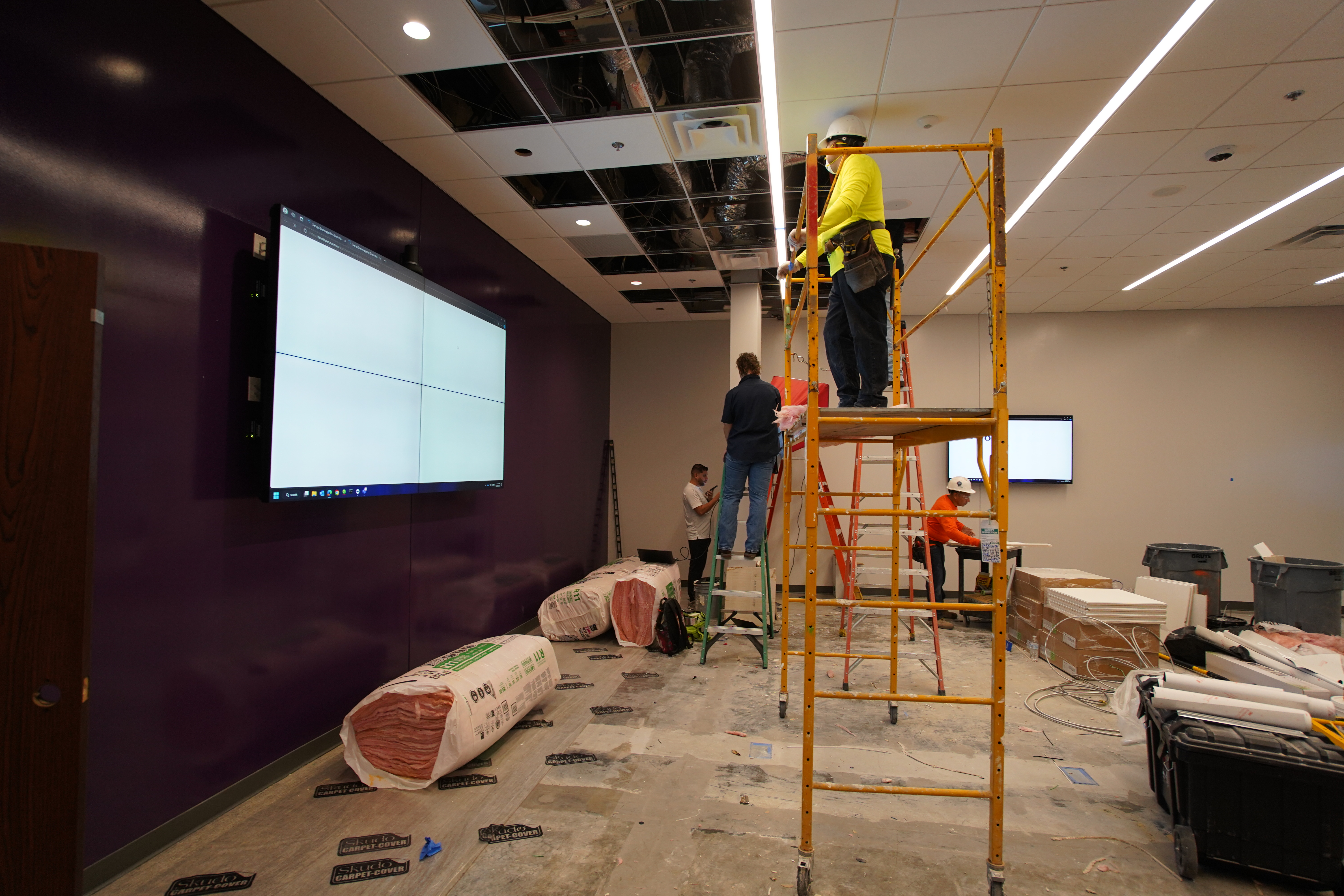 AV technicians installing displays and ceiling equipment in a commercial conference room