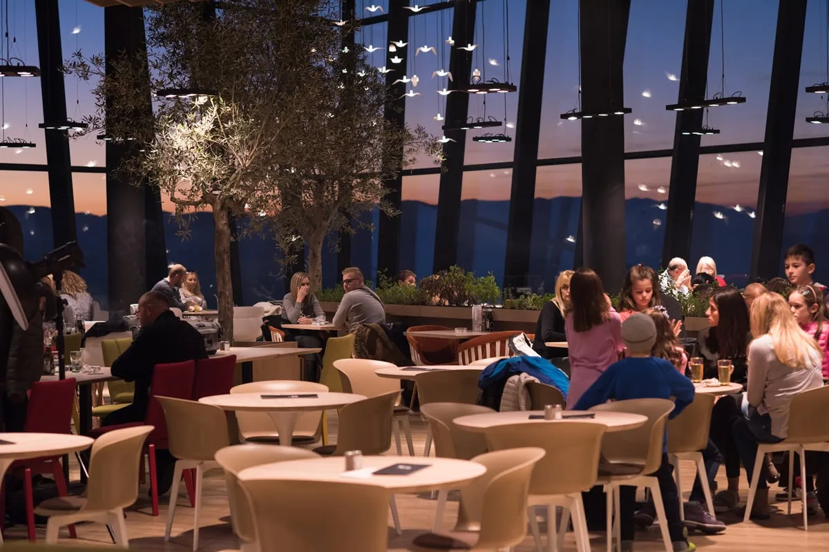 Crowded restaurant at sunset with modern decor.