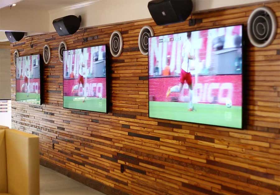 Closeup of three wall-mounted TV displays with speakers mounted above them