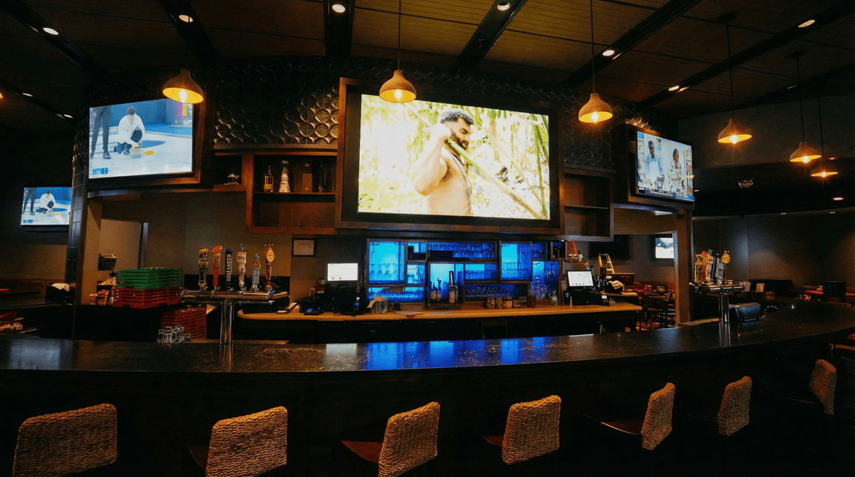 Cozy sports bar with multiple TV screens and seating.