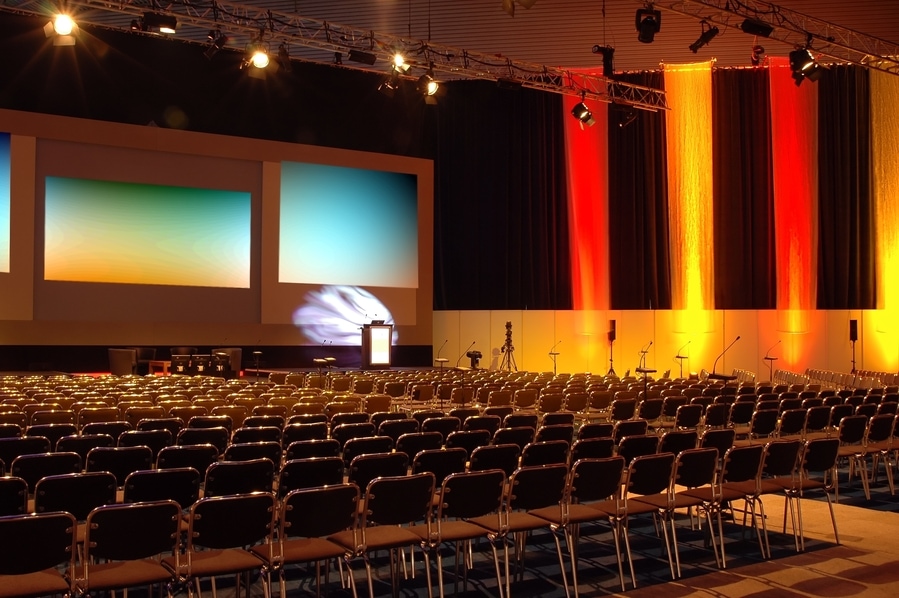 large conference hall auditorium with multiple seating rows and large video displays