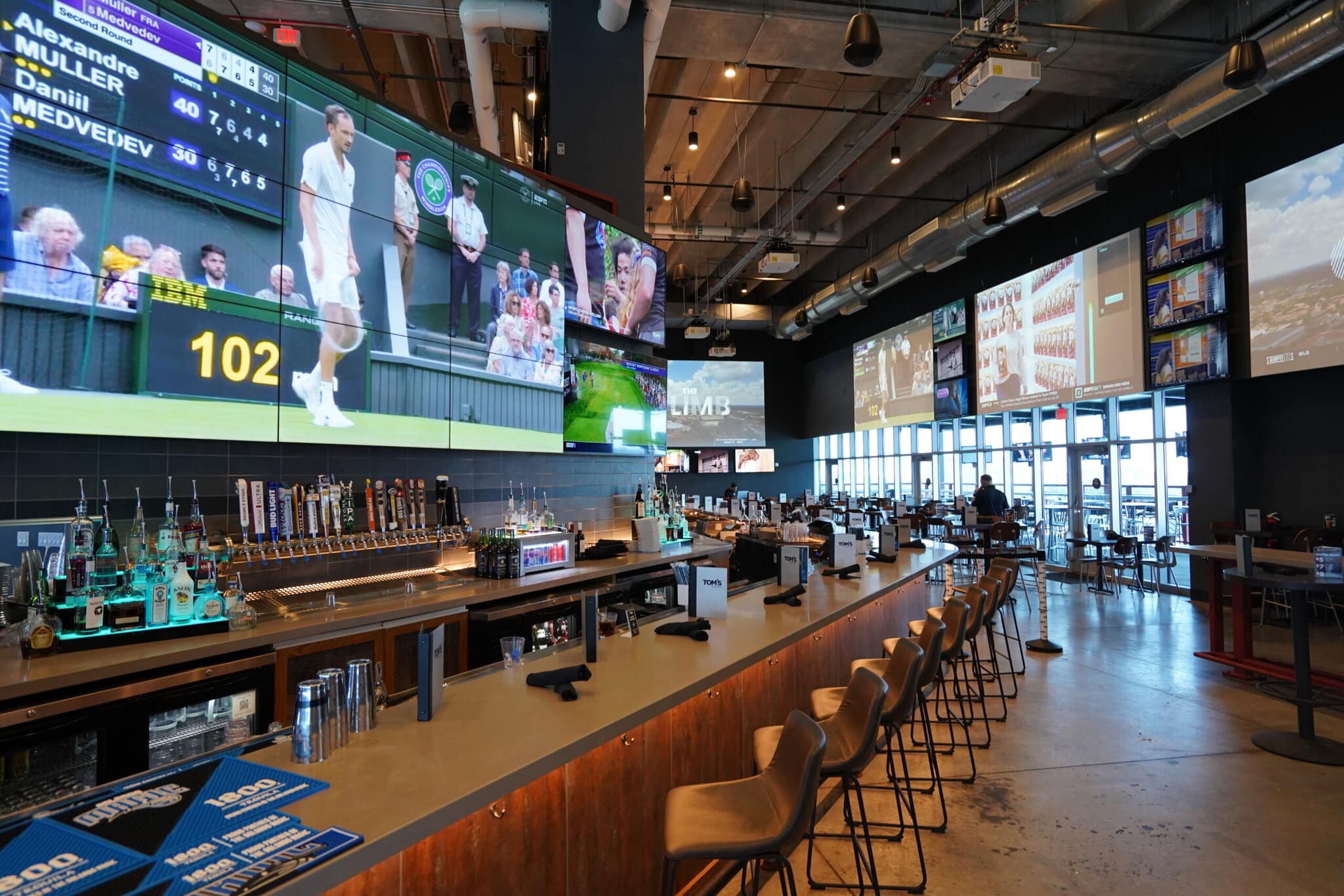 Bar with large screen TVs and seating area.