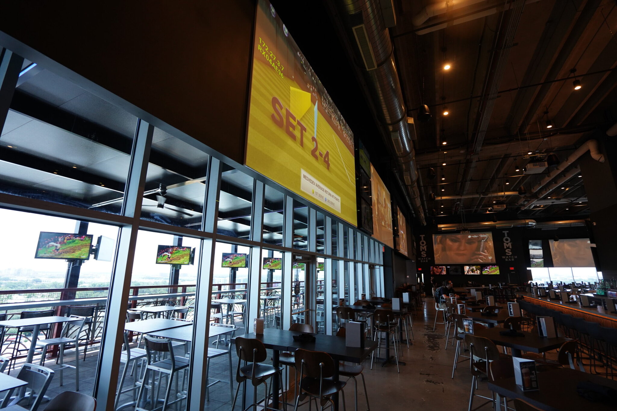 Sports bar interior with large screens displaying tennis.