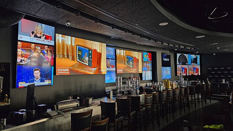 Bar with multiple TVs displaying various broadcasts.