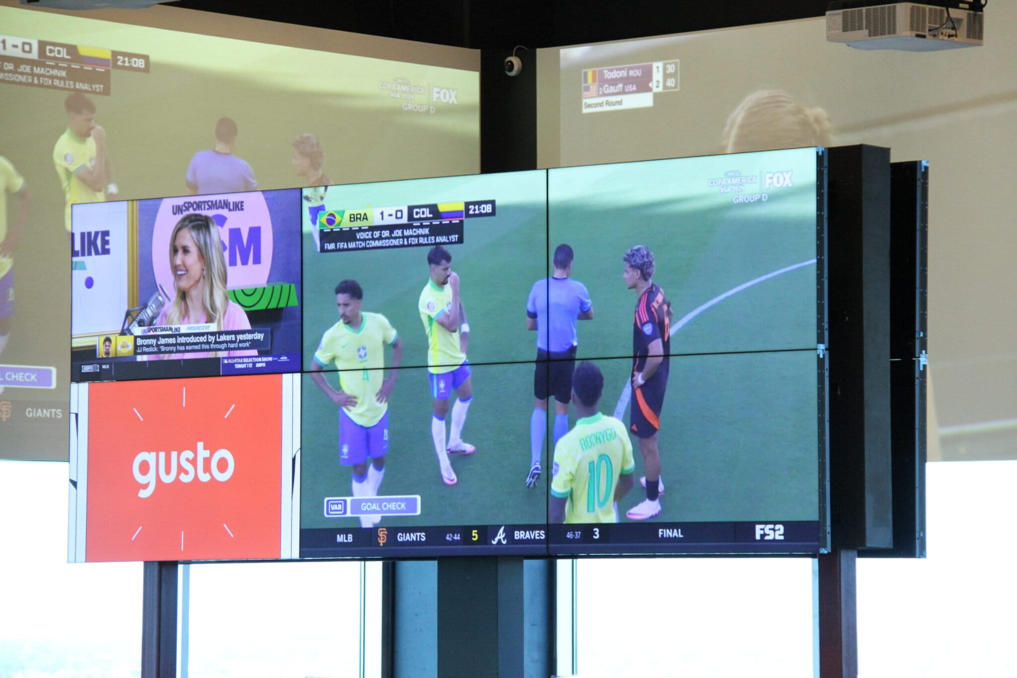 Multiple TV screens showing sports broadcast and news.
