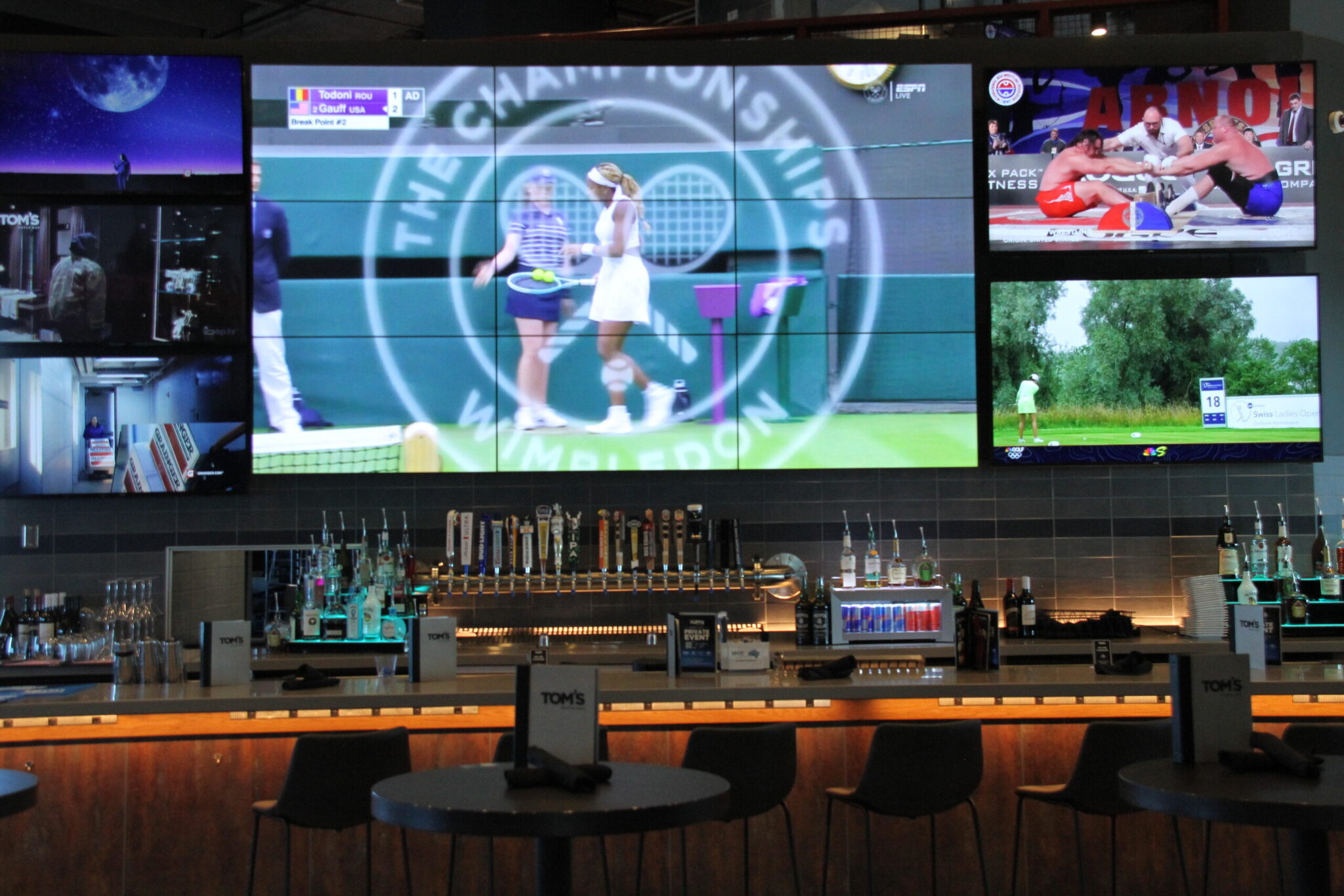 Sports bar with large TV screens and liquor bottles.