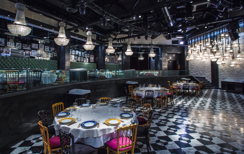 Elegant restaurant interior with chandeliers and checkered floor.