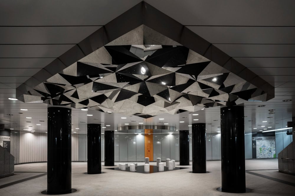 Modern underground hall with geometric ceiling design.
