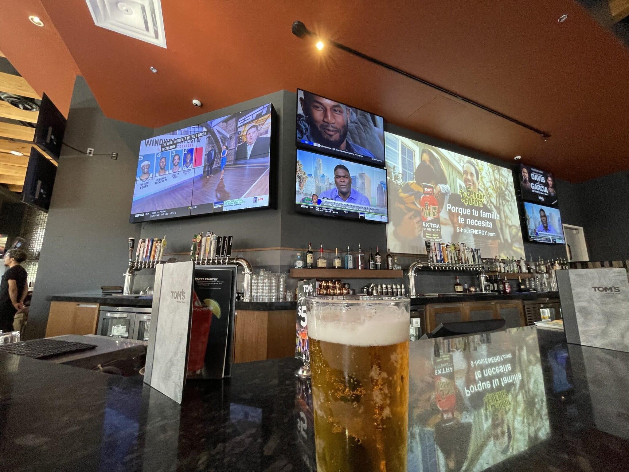 Bar counter with TV screens and drink menu.