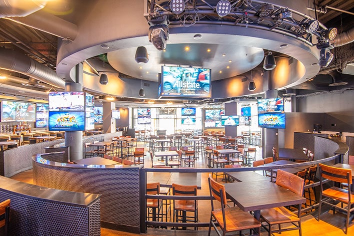 Spacious sports bar with TV screens and tables.