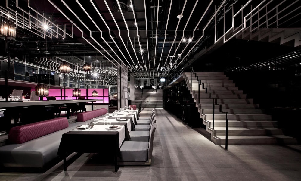 Modern restaurant interior with elegant lighting and staircase. a low voltage lighting solution powered by an av control system