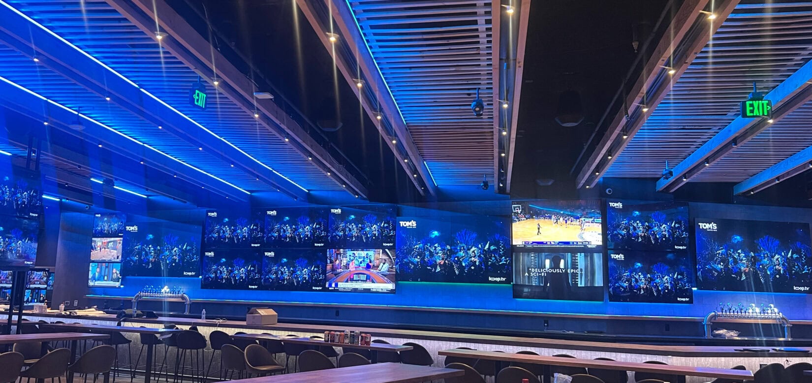 Modern sports bar with multiple TV screens and seating.