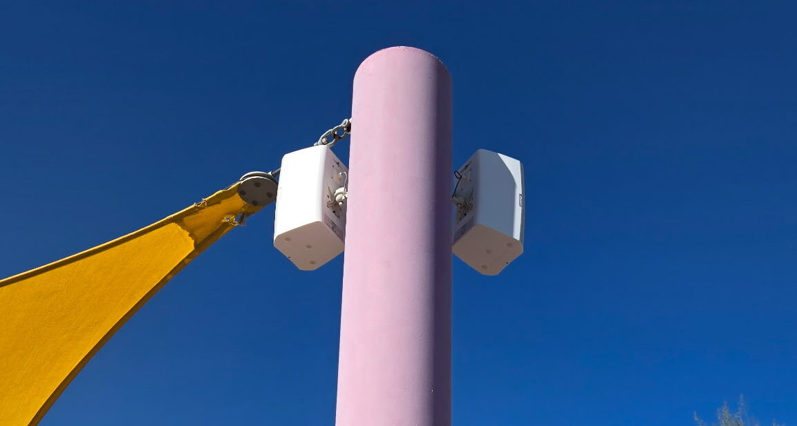 Pink pole with canopy in sunny outdoor area.