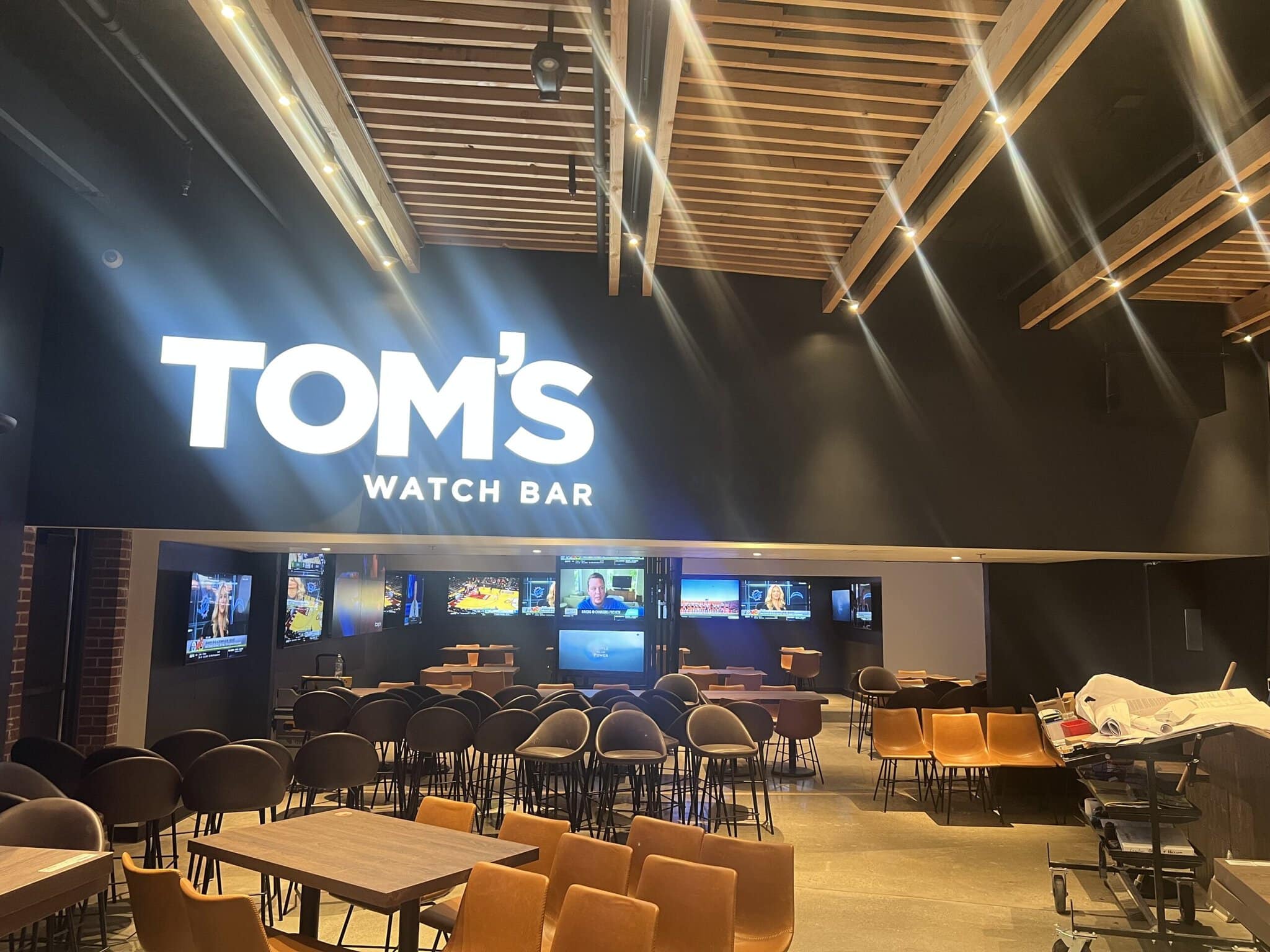 Interior of Tom's Watch Bar with seating and TVs.