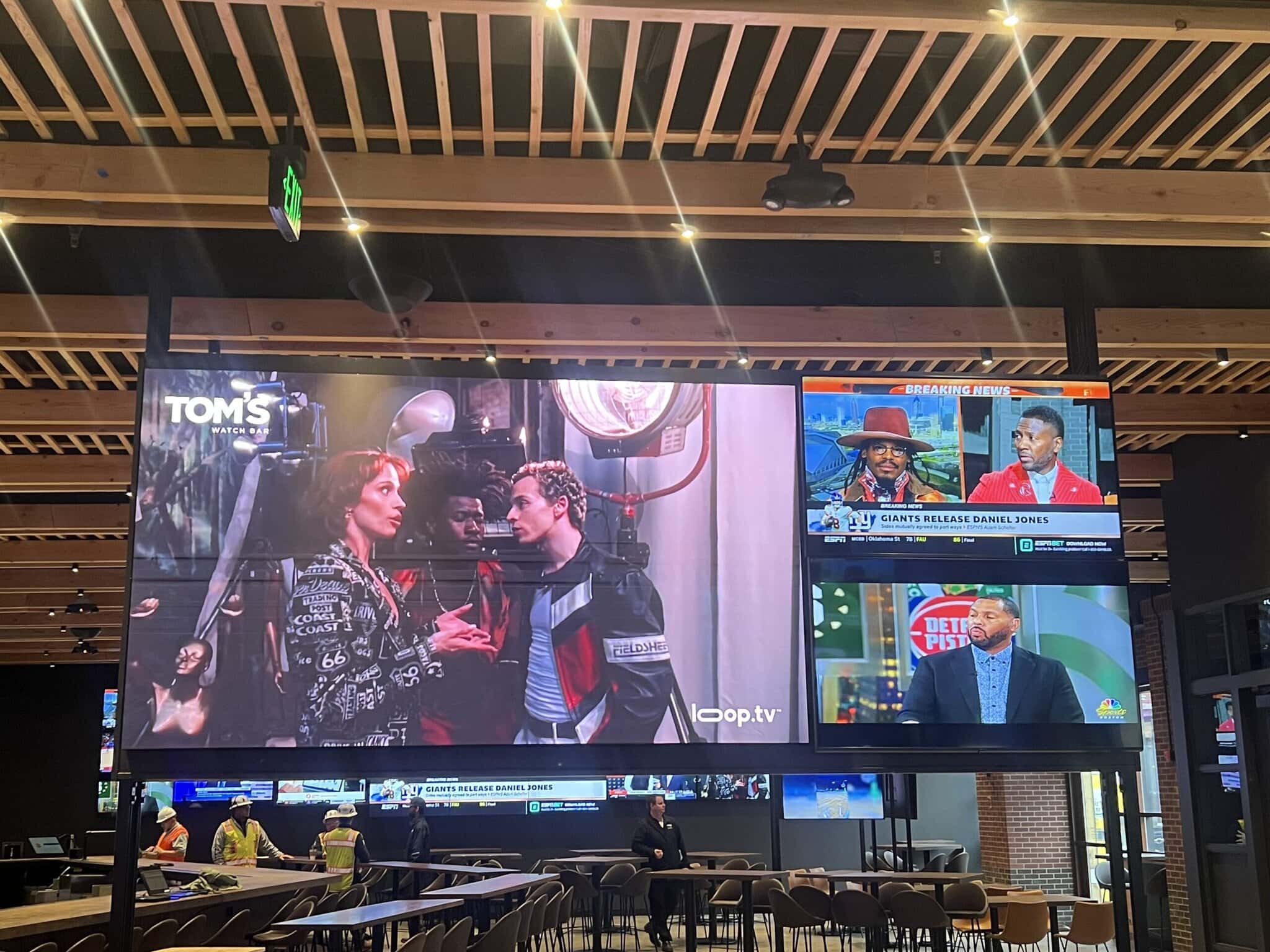 Large digital screens displaying various shows in a venue.