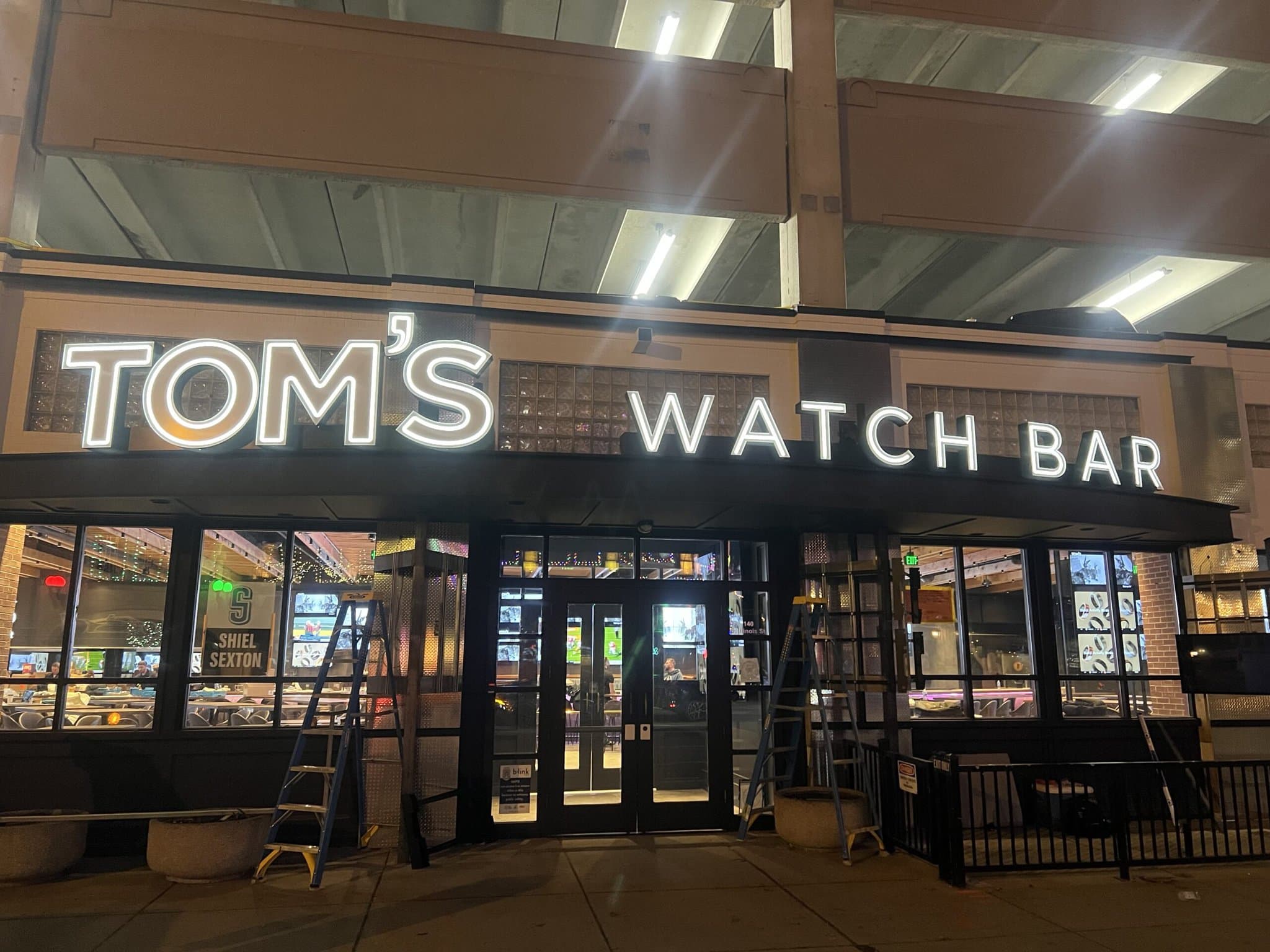 Tom's Watch Bar entrance with neon sign.