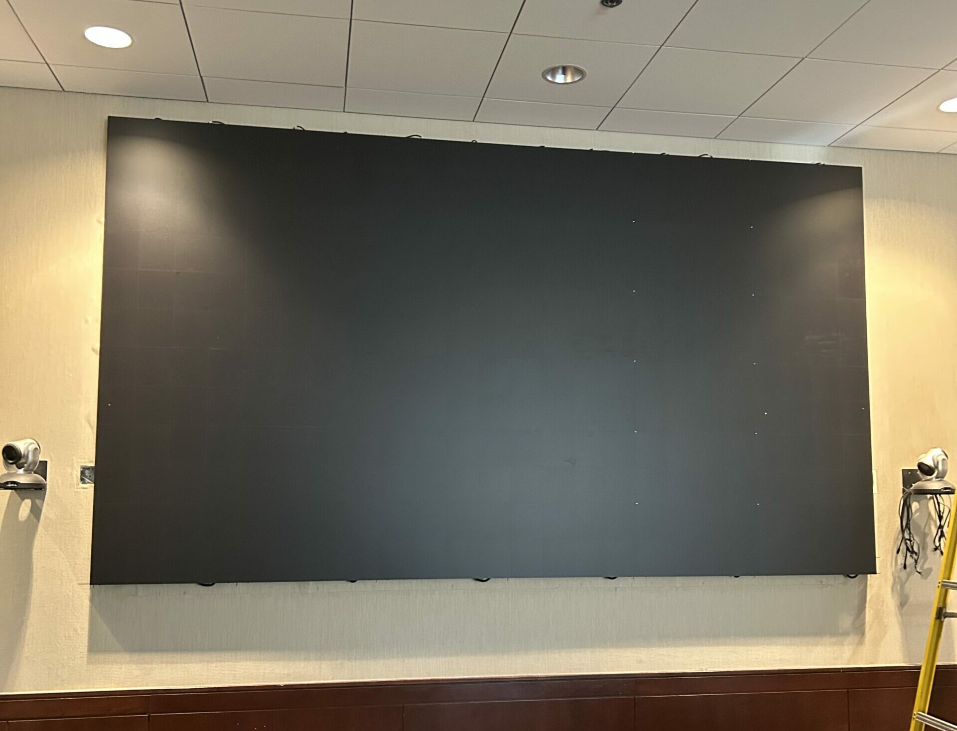 Large black screen mounted on wall indoors.