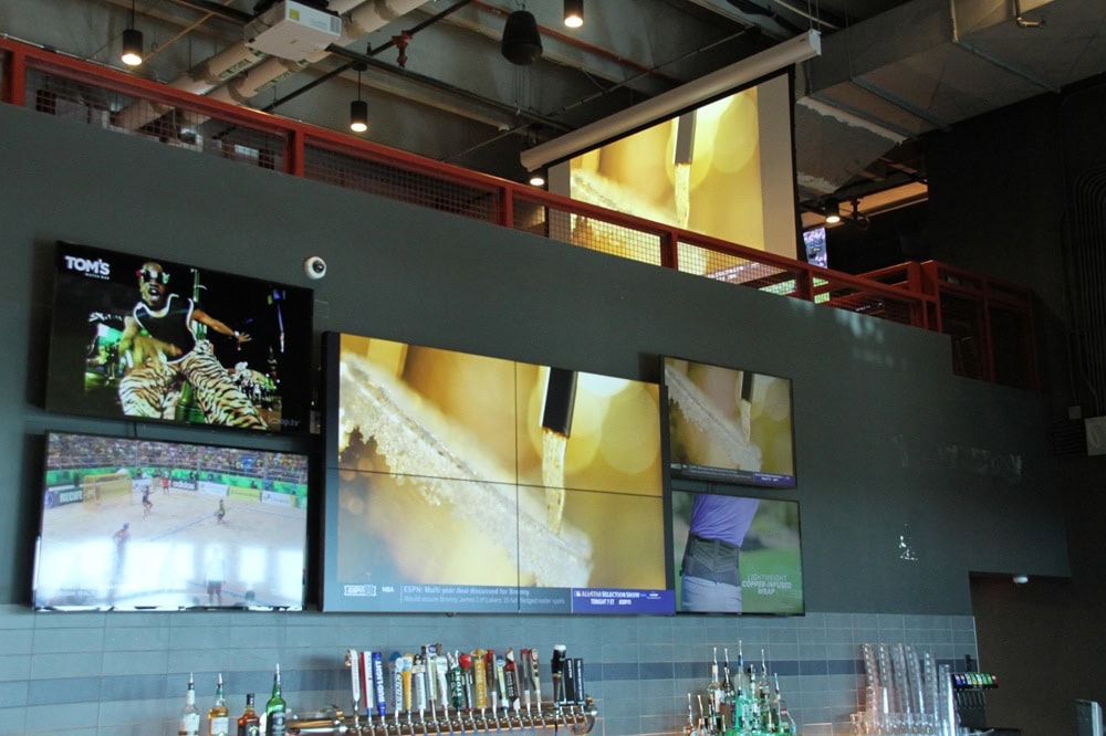 Bar with multiple TV screens and drink taps.