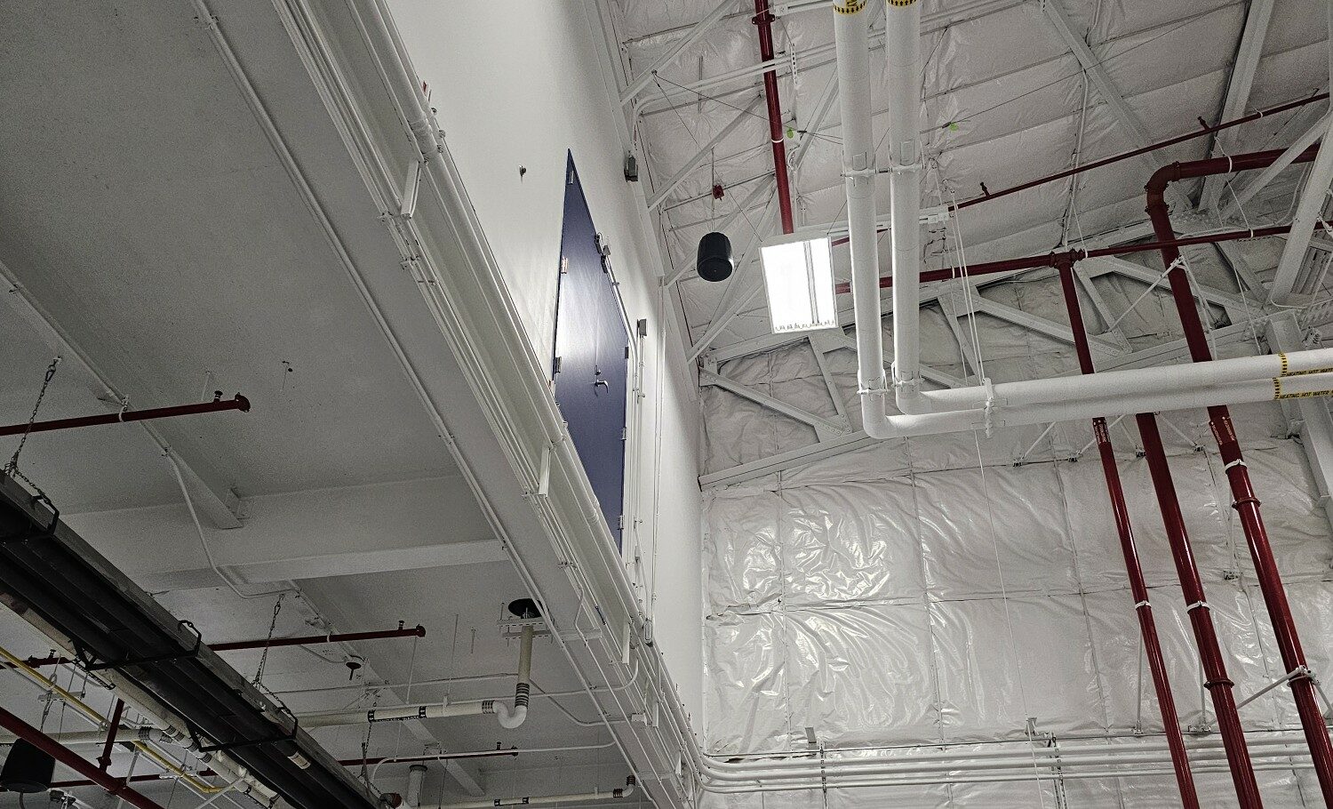 Industrial ceiling with pipes and overhead lights.