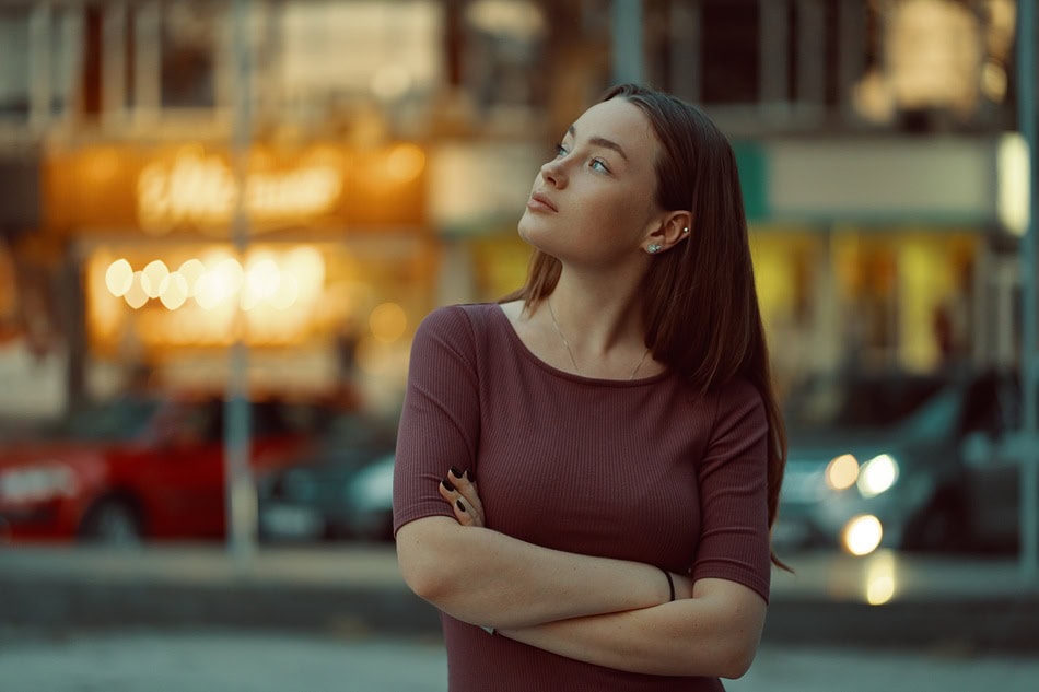 Woman looking thoughtful outdoors in urban environment.
