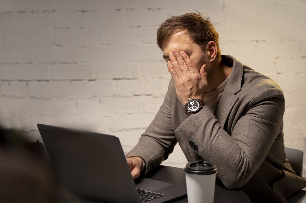 Frustrated man at laptop with coffee