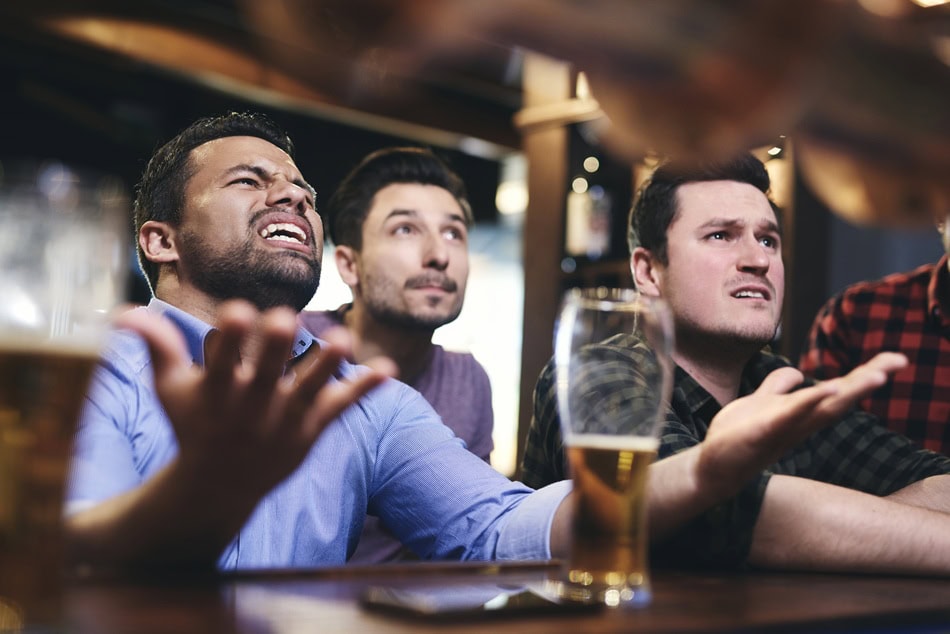 Upset friends watching sports at a bar.