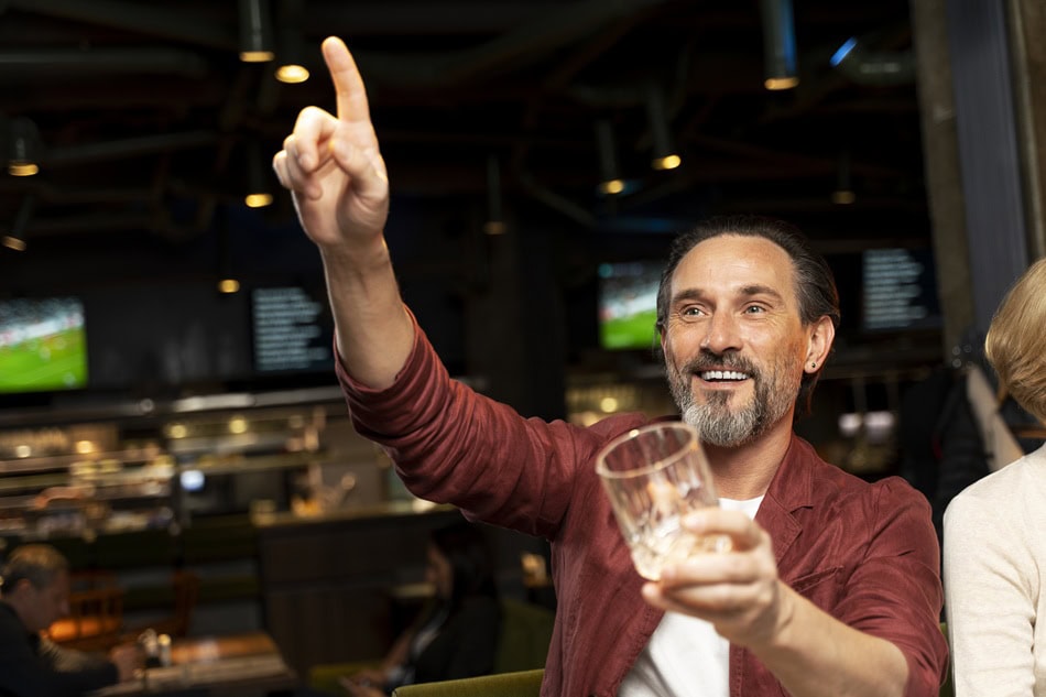 Man cheering with empty glass in a bar.