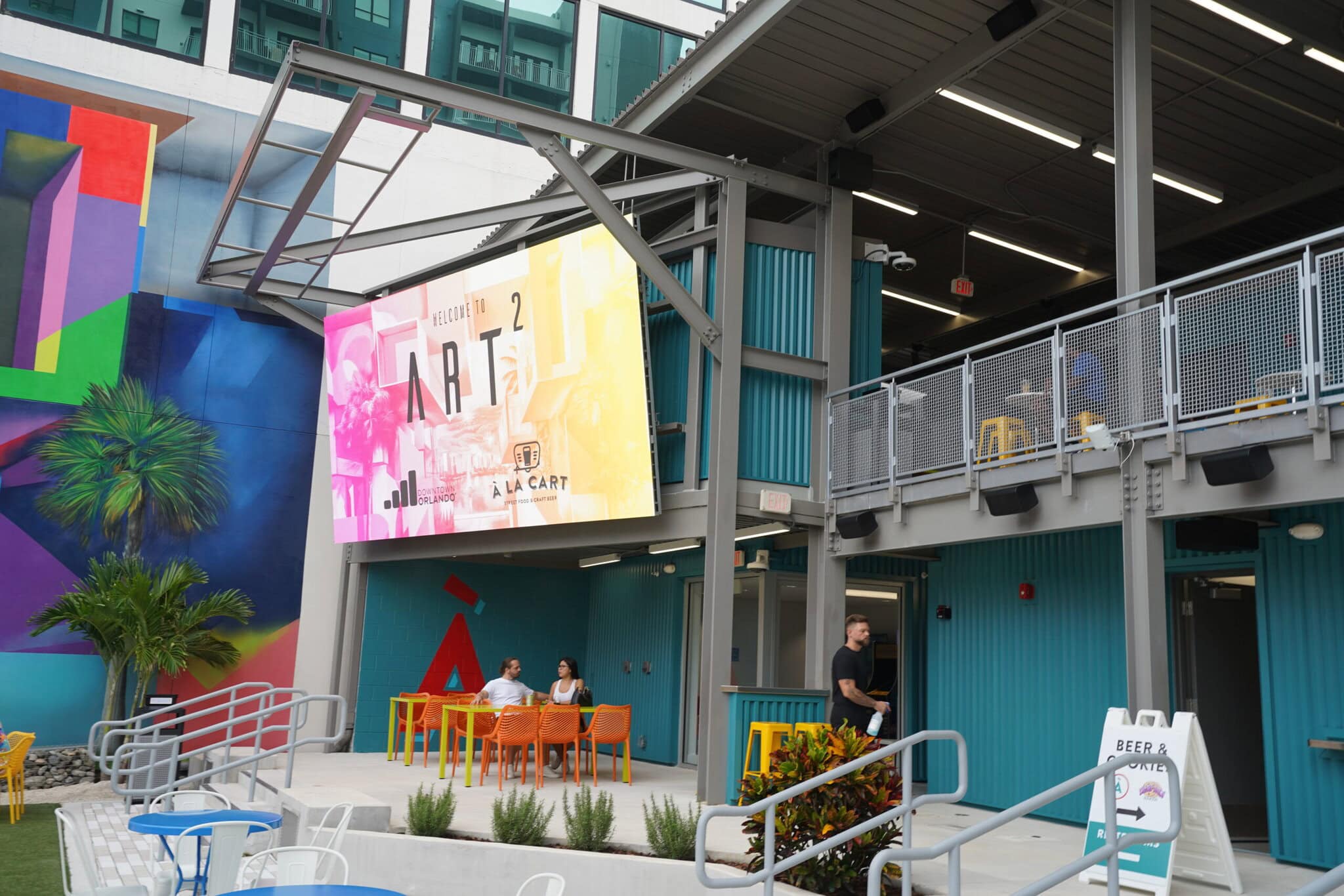 Outdoor seating at colorful artistic venue with giant digital display led video wall