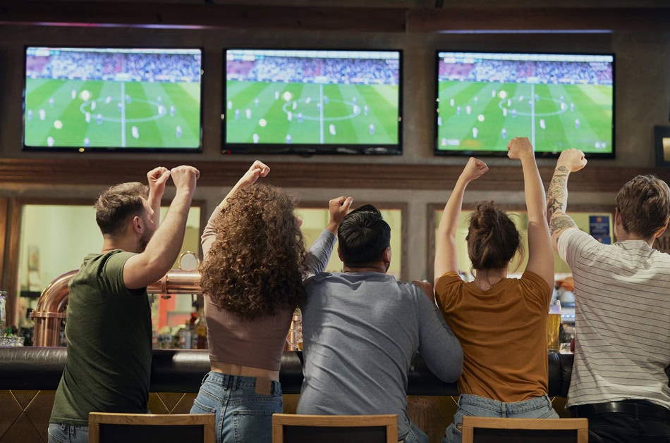 Fans cheering soccer match in sports bar multiple TVs