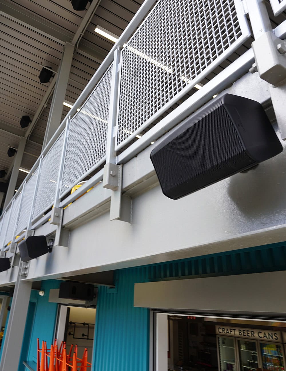 Outdoor speakers mounted on building with blue wall.