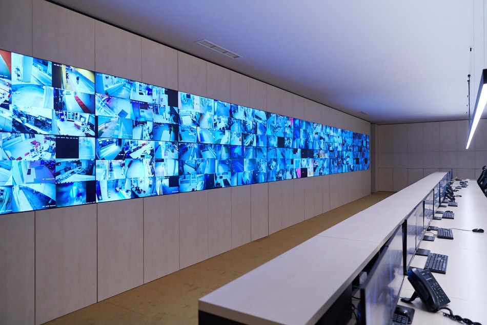 Surveillance control room with multiple video screens.