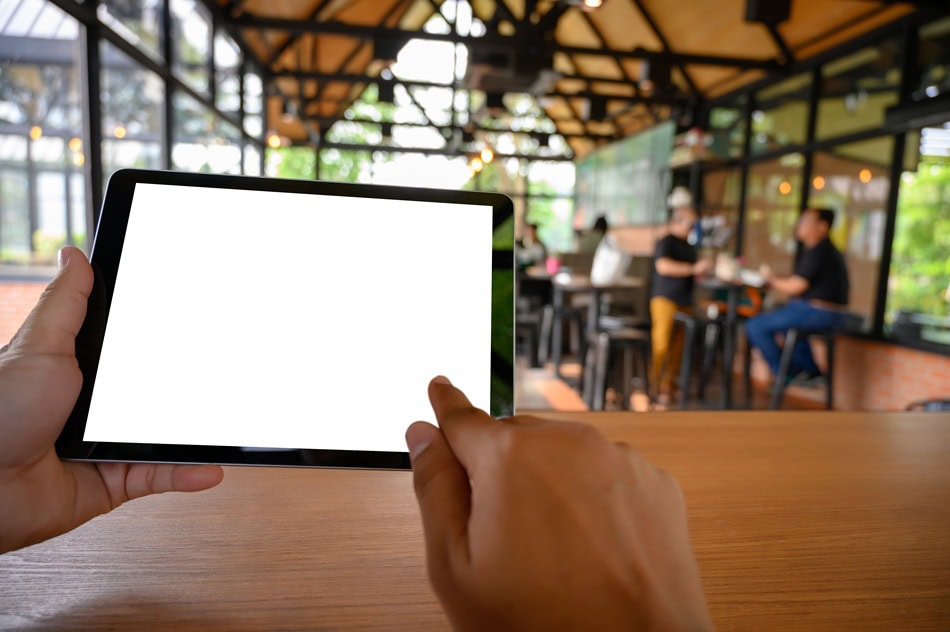 Person using tablet in modern café setting.