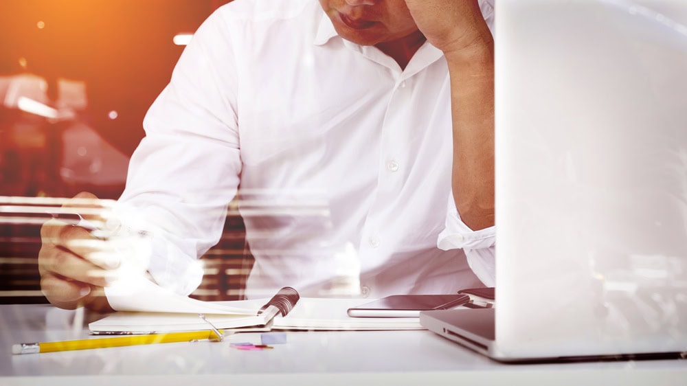 Person working at desk with laptop and papers.