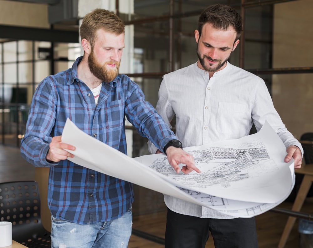 Two men reviewing architectural blueprints in office.