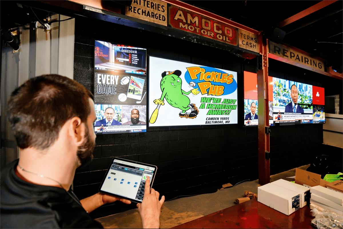 Man using tablet at sports bar with TVs.