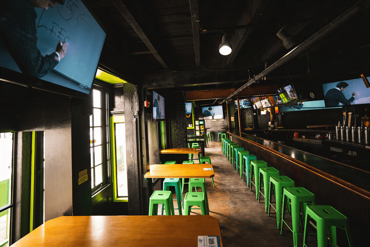 Empty bar with green stools and TV screens