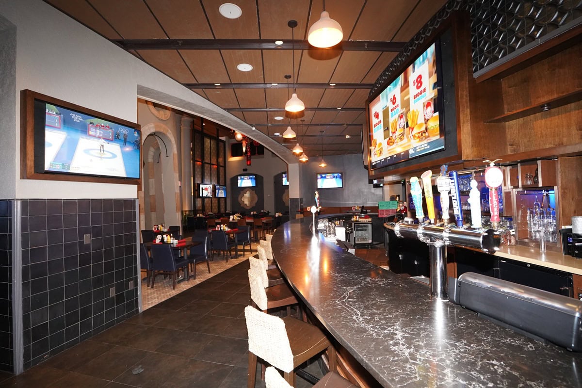Modern sports bar with beer taps and screens.