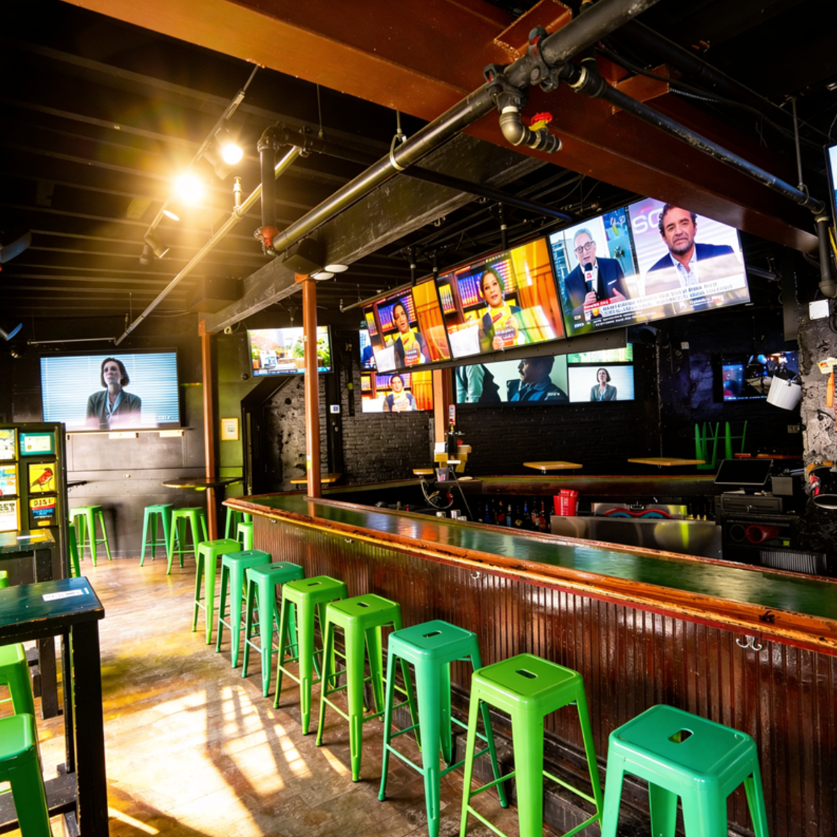 Bar with green stools, multiple TV screens.