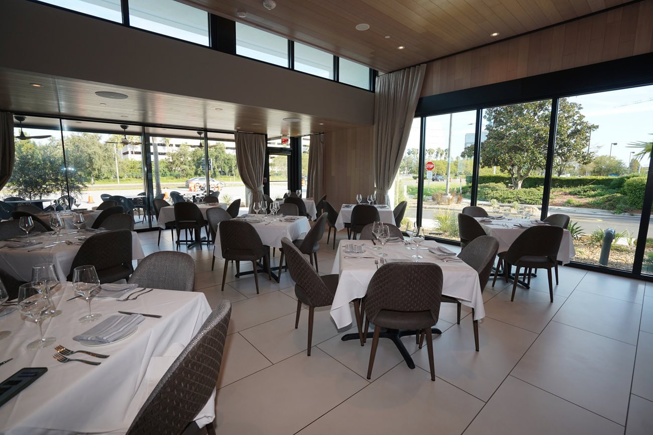 Modern restaurant with outdoor view and set tables.